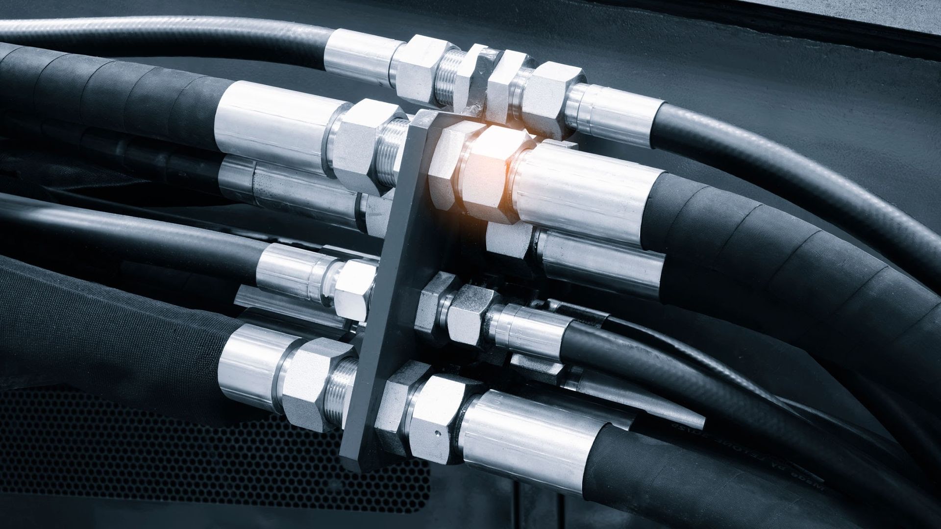 Close-up of black hydraulic hoses with silver metal couplings connected together.