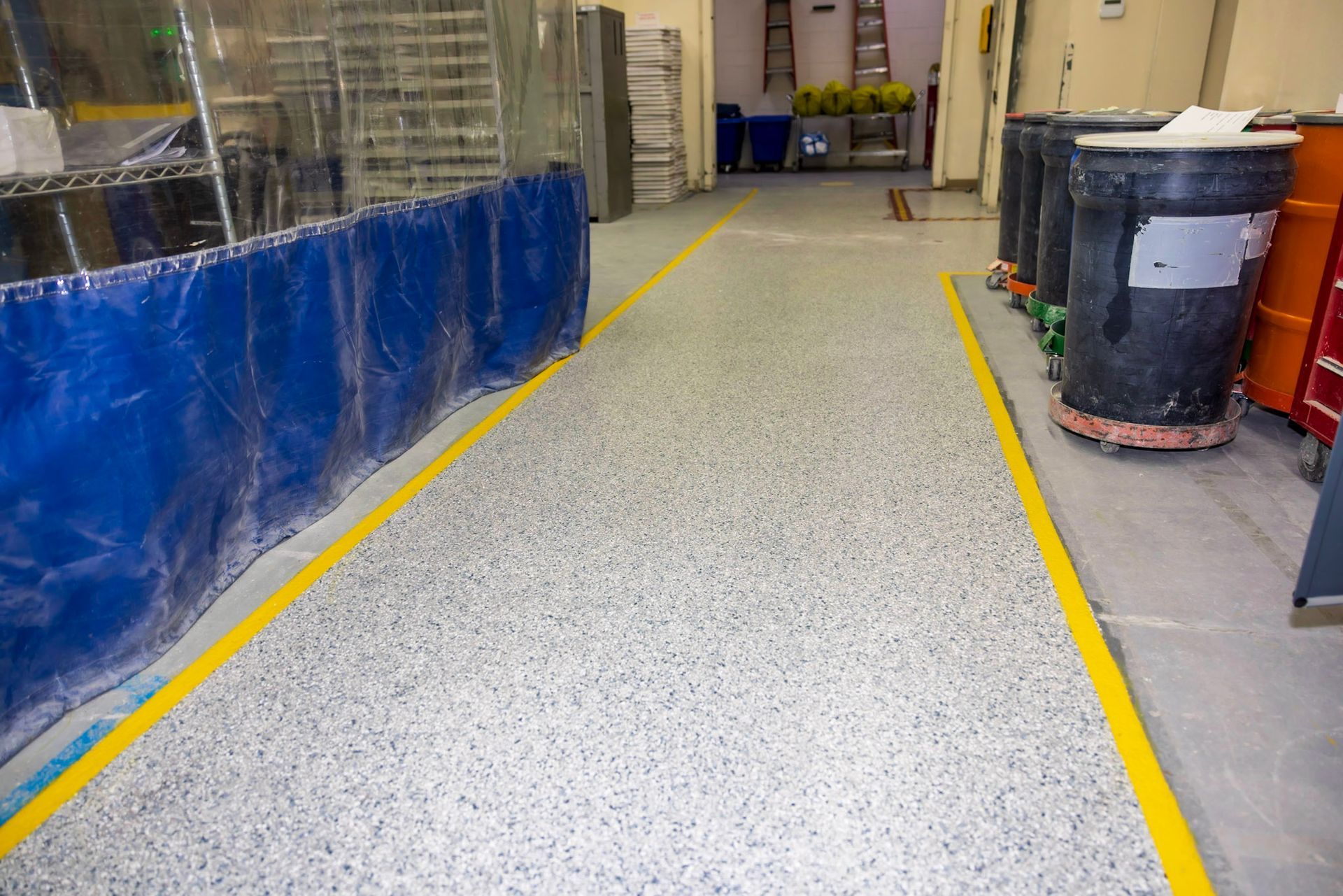 a warehouse with a yellow line on the floor and a blue curtain .
