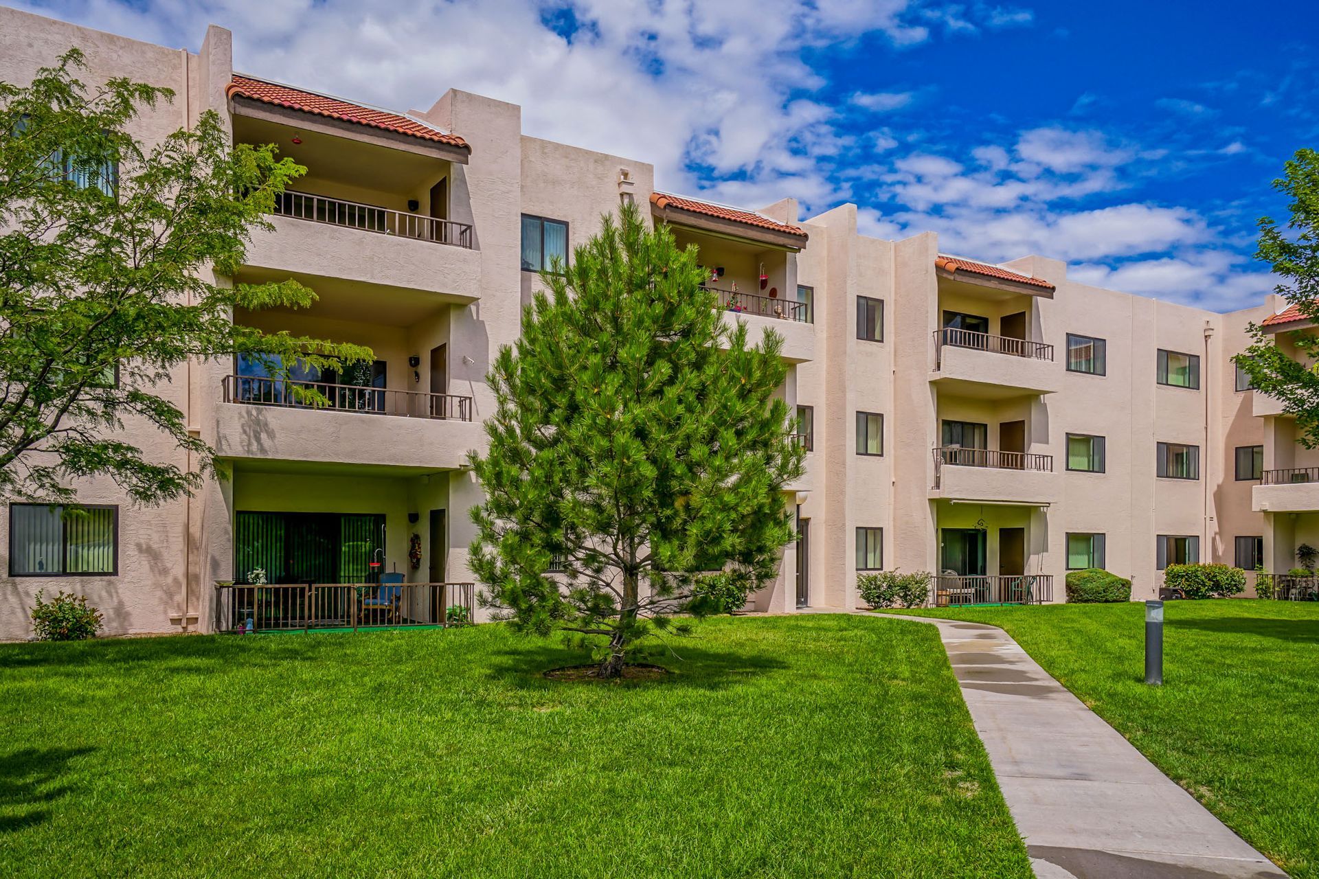 a large apartment building with a lush green lawn in front of it .