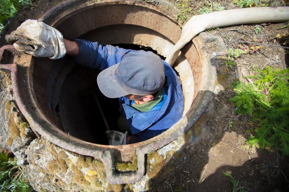 operatore che pulisce fossa biologica