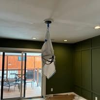 White bag hanging from a ceiling fixture in a green room with sliding glass doors to a patio