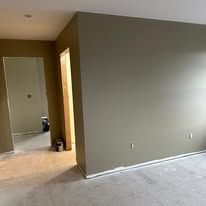 Empty beige room with tiled floor and open doorway leading to a hall