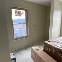 Partially finished room with beige walls, a window, and boxes on the floor