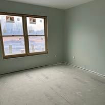 Empty light-gray room with a window letting in daylight