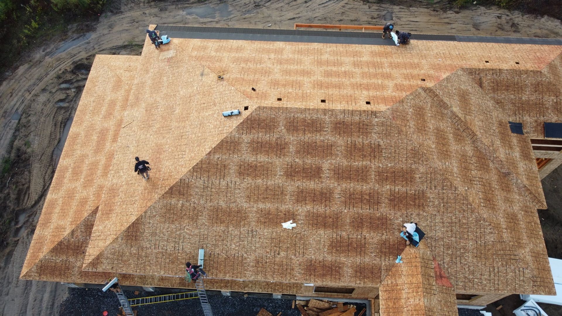 Une vue aérienne d'un toit en cours d'installation sur une maison en construction.