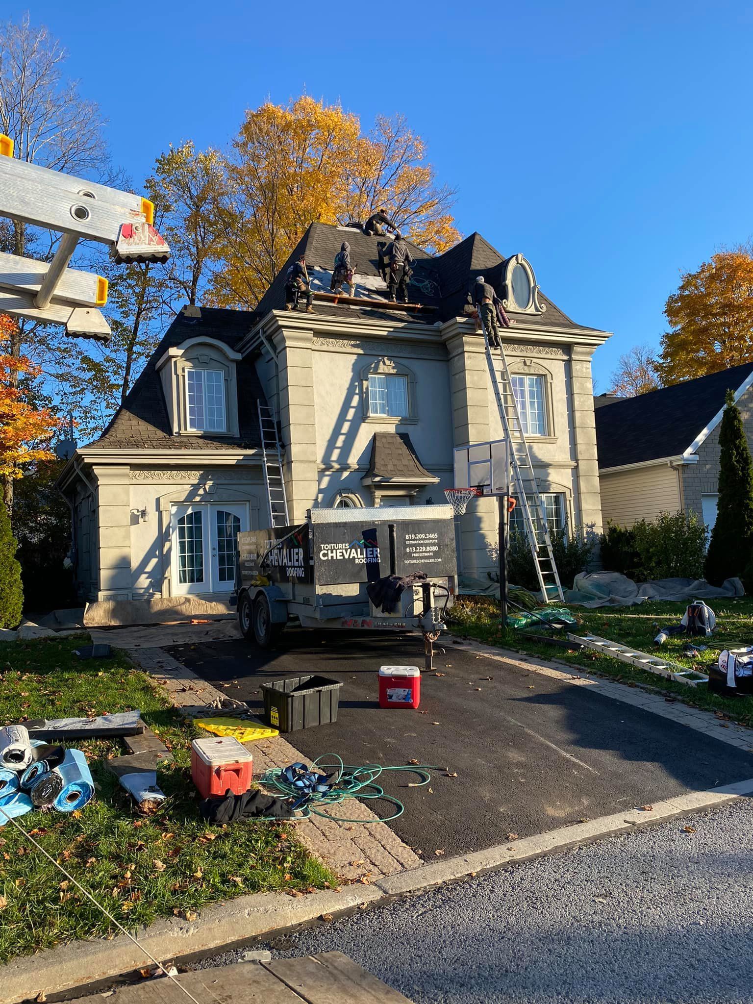 Une grande maison est en cours de rénovation avec un camion garé devant.
