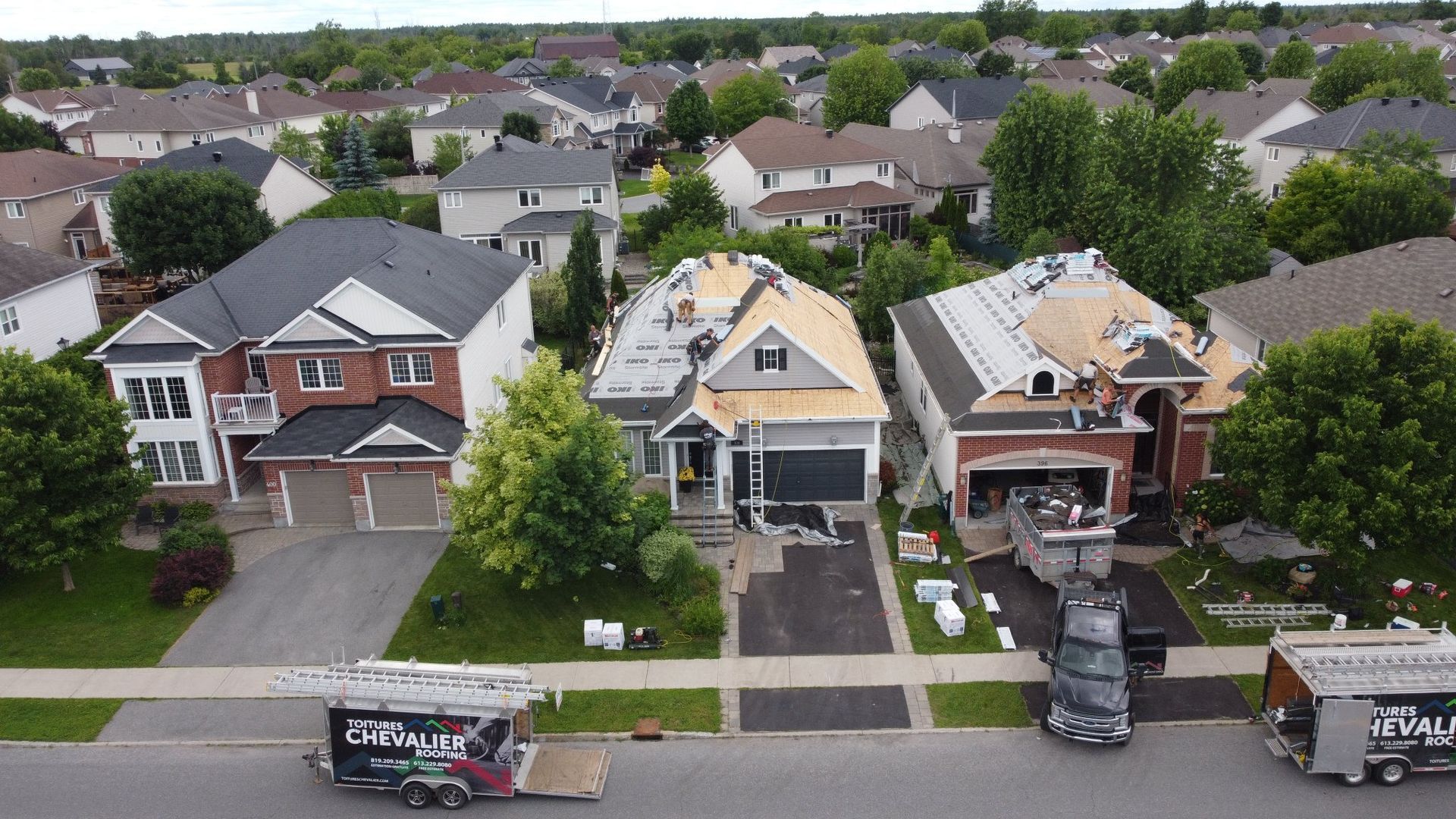 Une vue aérienne d'un quartier résidentiel avec un toit en cours d'installation sur une maison.