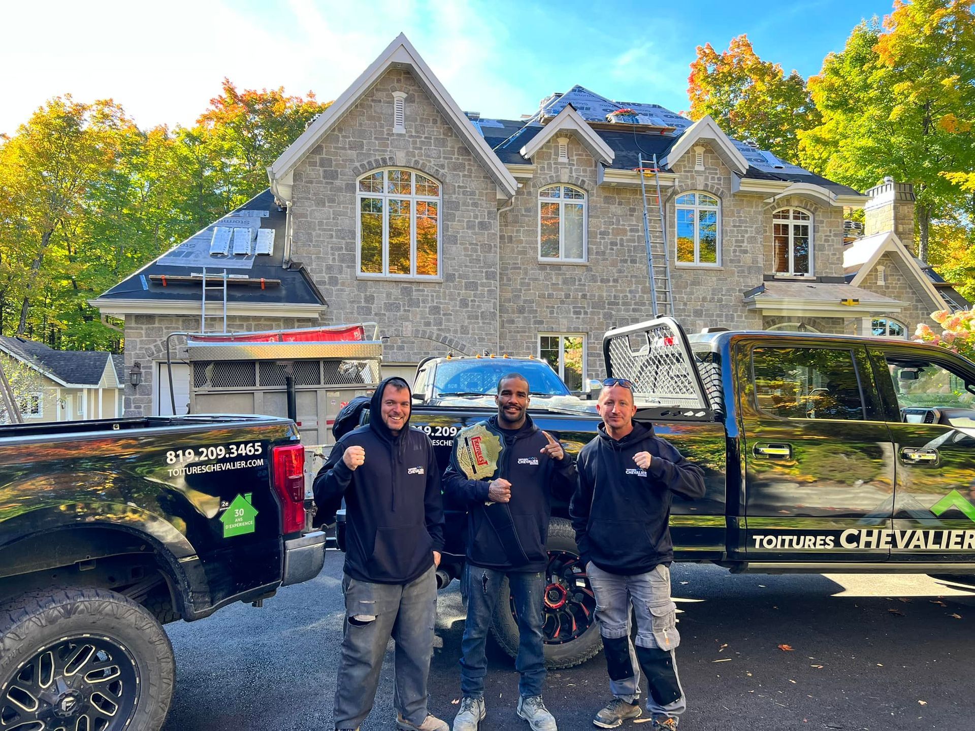 Trois hommes se tiennent devant un camion devant une grande maison.