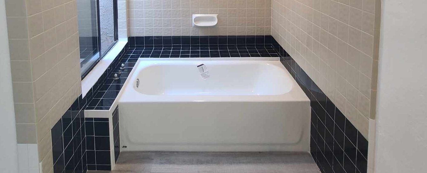
Image of a bathtub before refinishing. You can see black bath tile and the bathtub in the center.