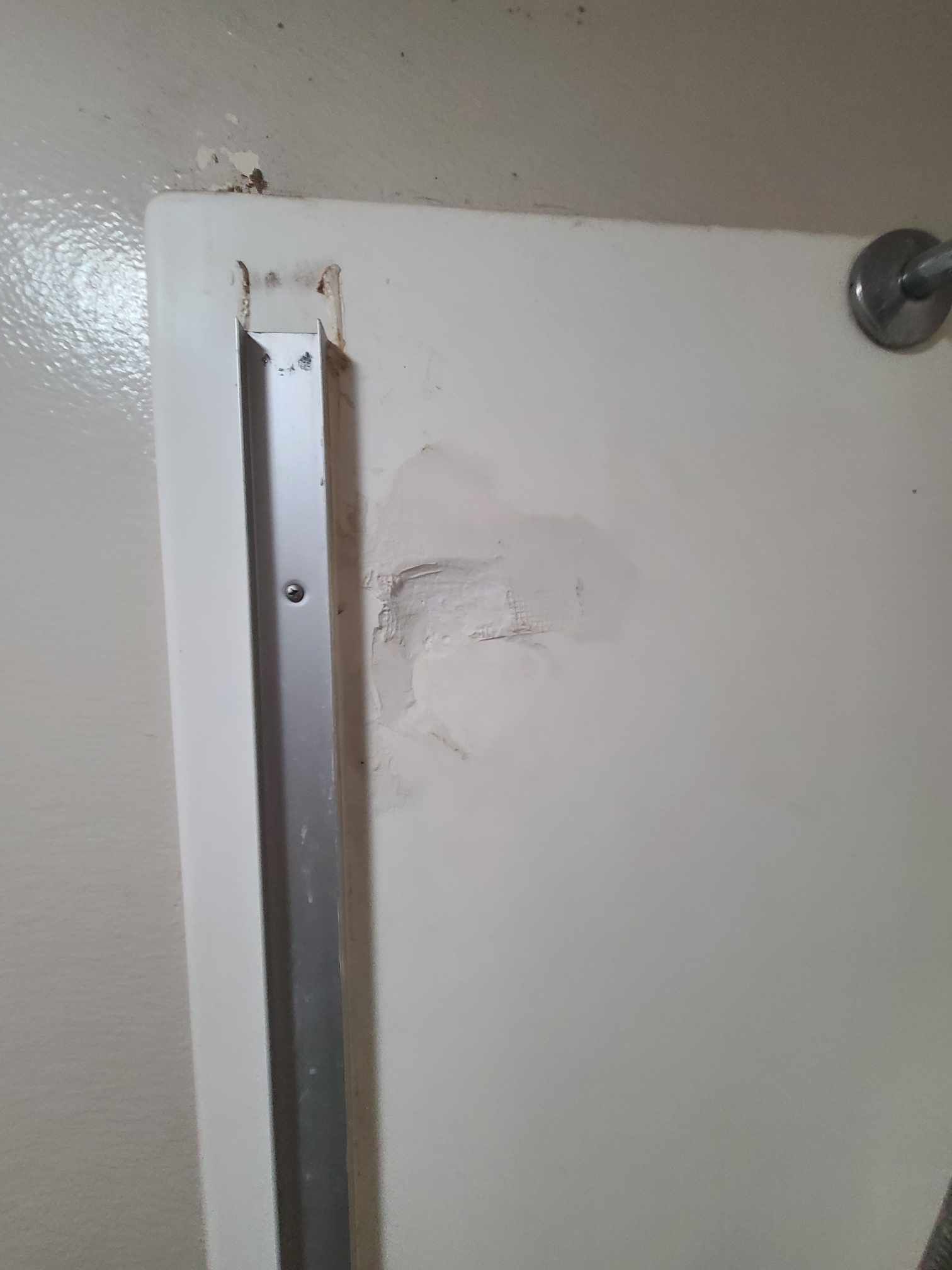Image of  shower tile wall that needs repair. You can see the tile has a hole.