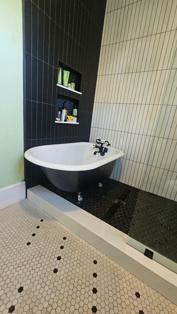 Picture of a bathtub that has been refinished. You can see a clawfoot bathtub in a bathroom with black and white tile.