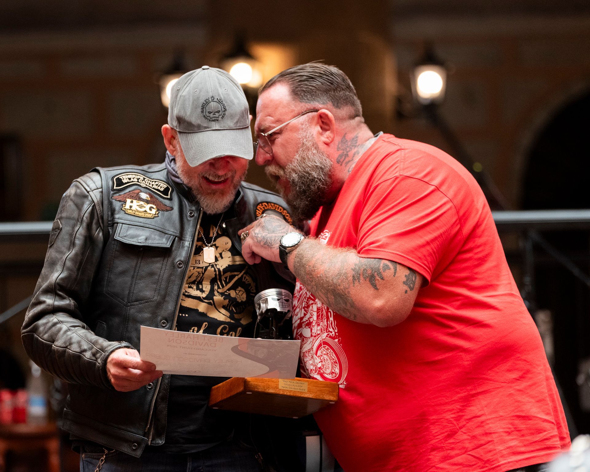 Two men are standing next to each other looking at a piece of paper.