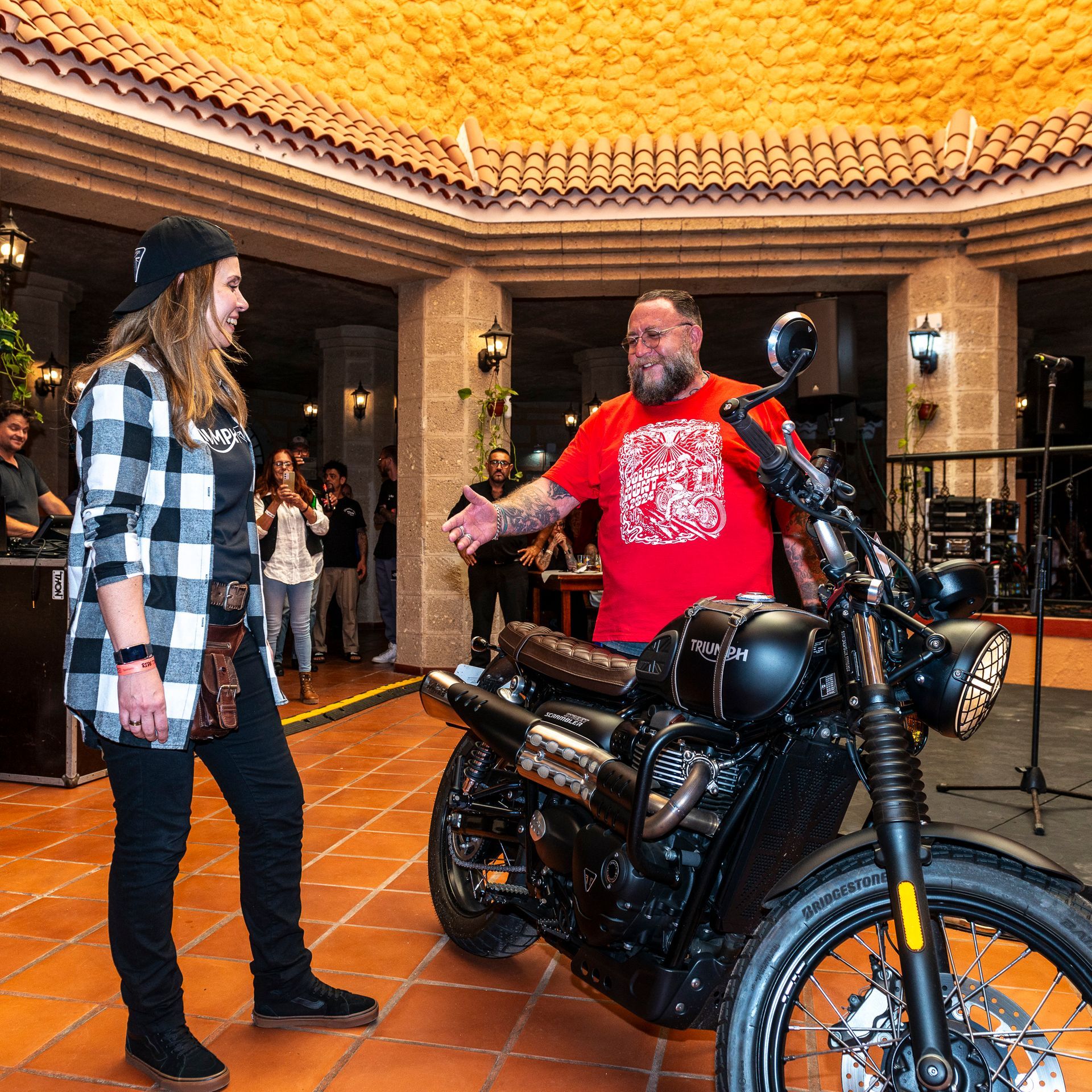 A man in a red shirt is standing next to a motorcycle