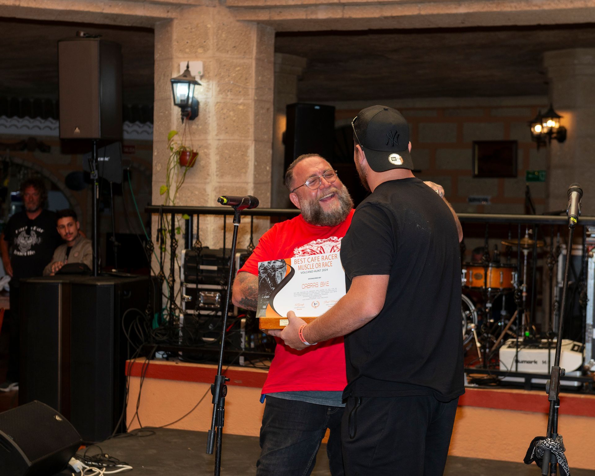 A man in a red shirt is hugging another man in a black shirt