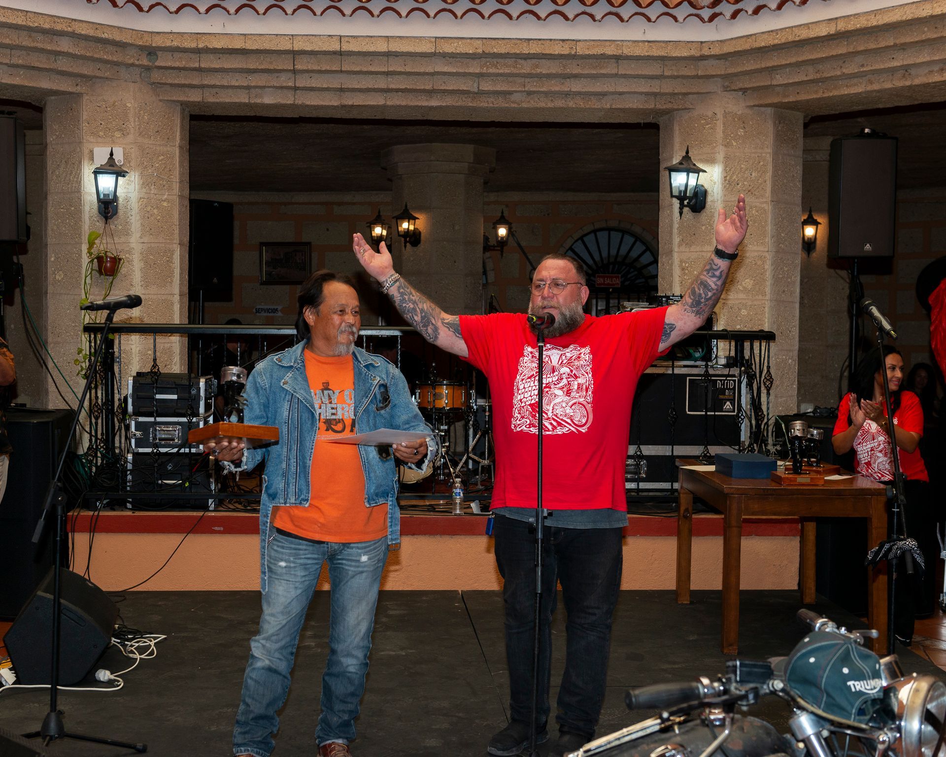 A man in a red shirt stands next to another man