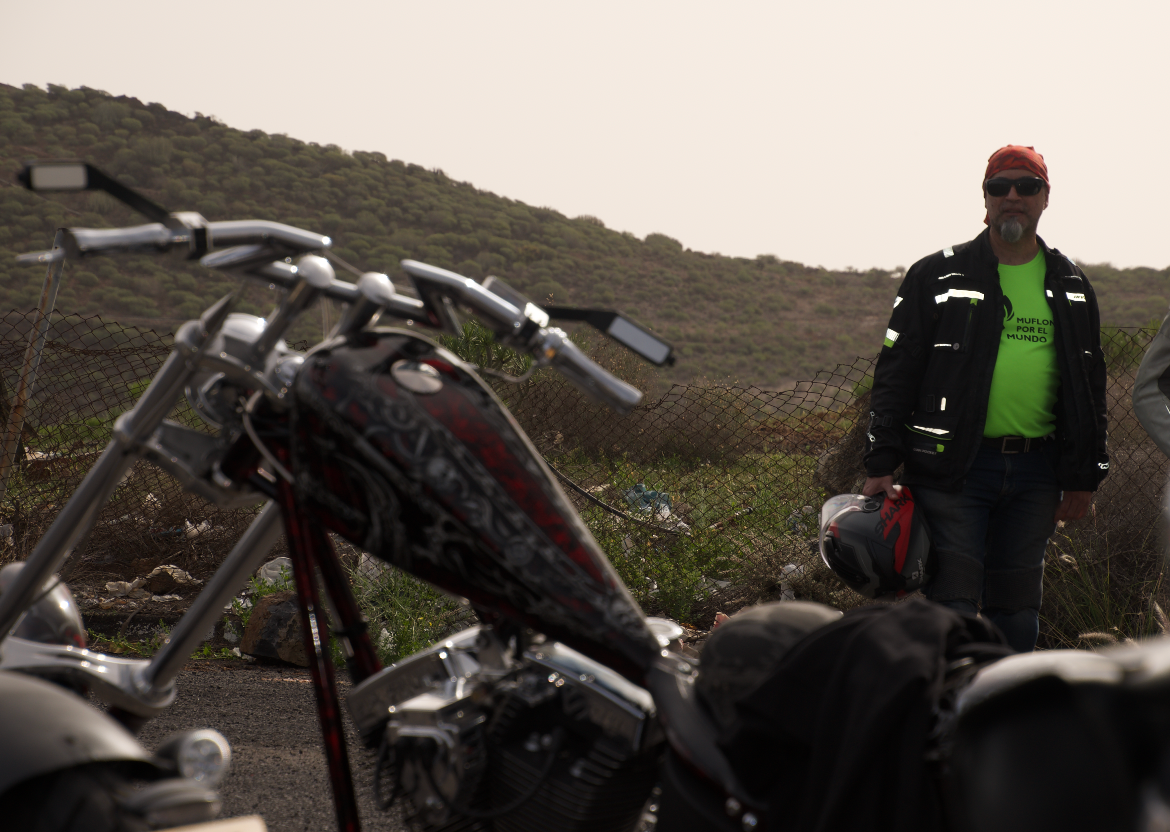 A man in a neon green shirt is standing next to a motorcycle
