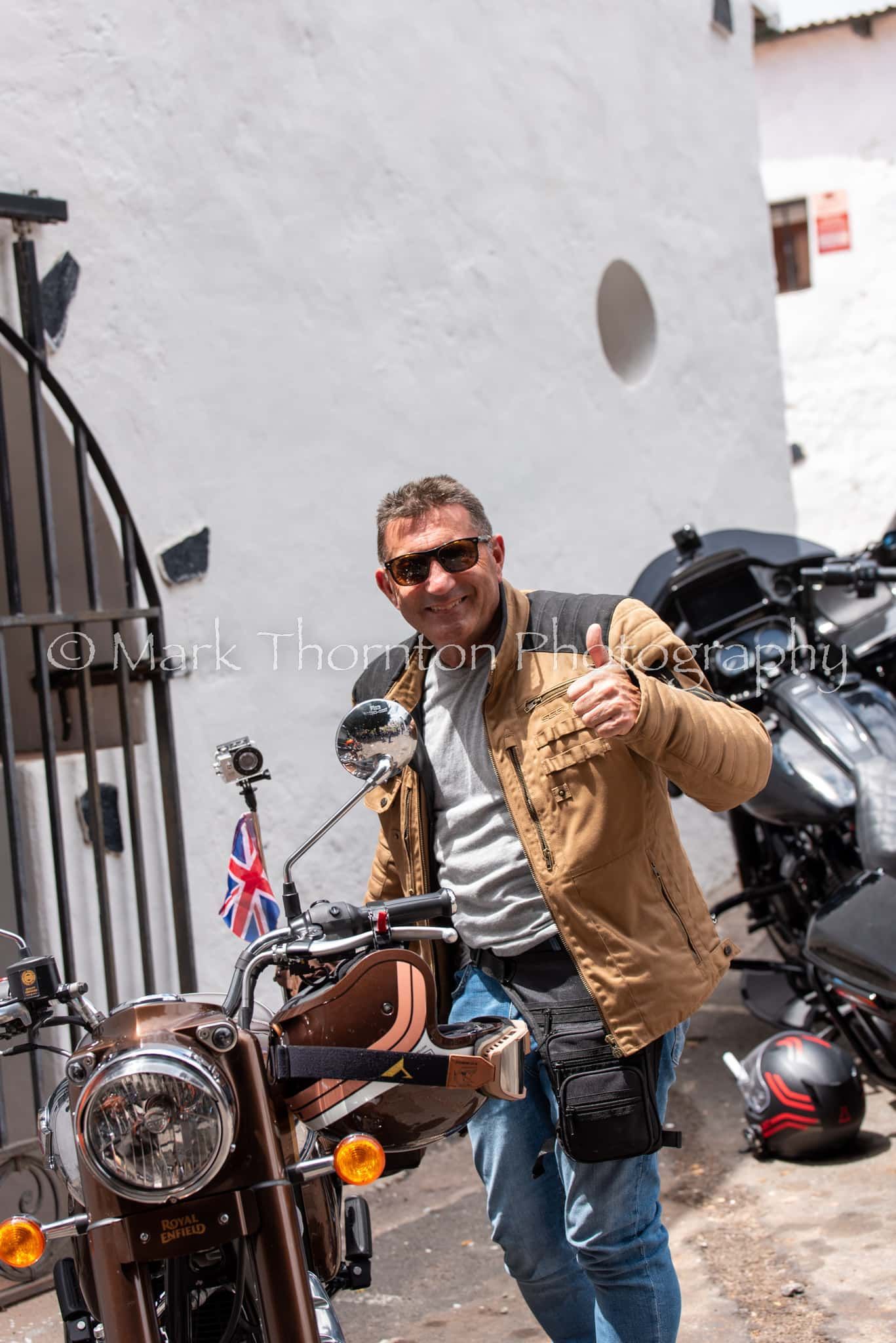 A man is standing next to a motorcycle and giving a thumbs up.