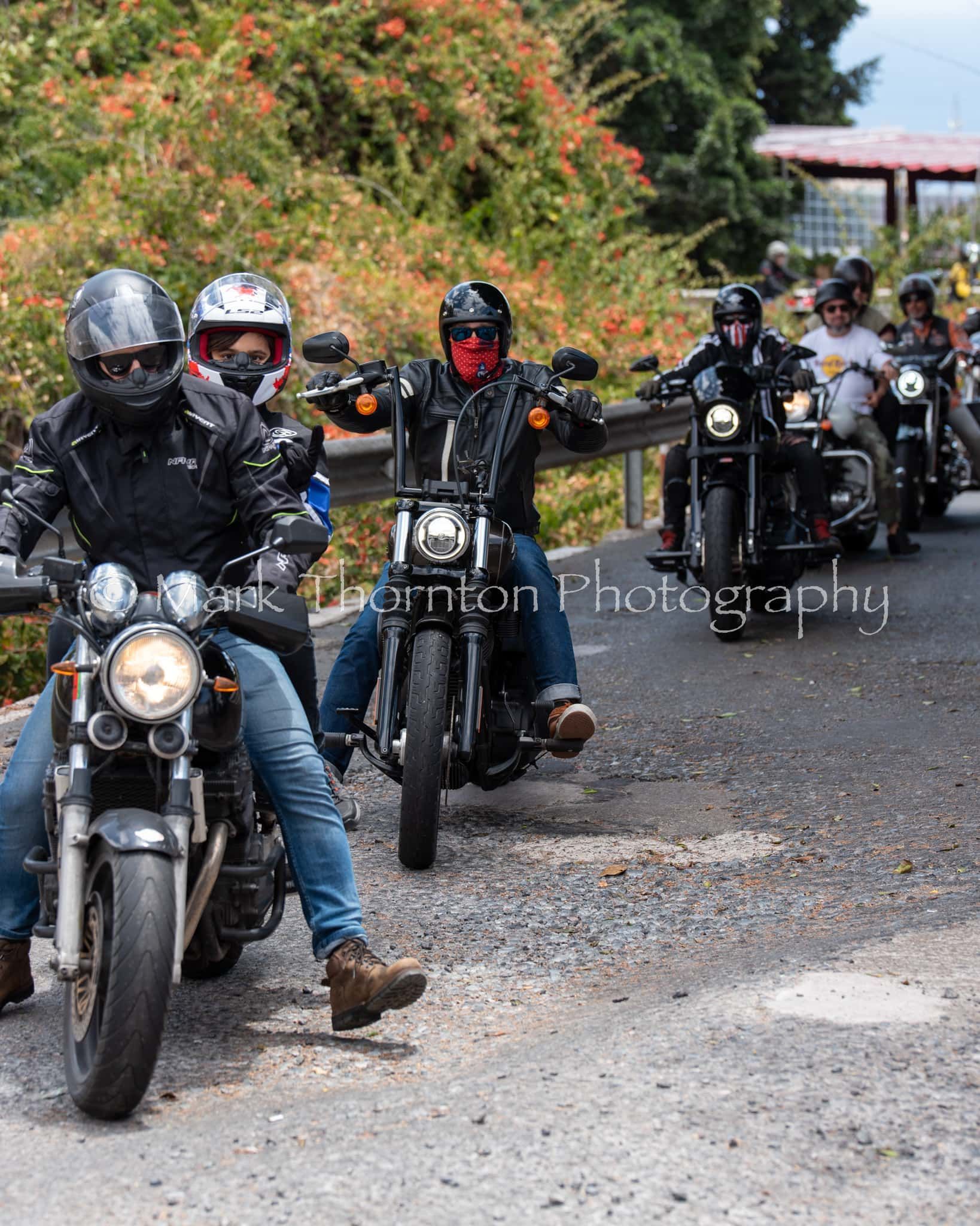 A group of people are riding motorcycles down a road.