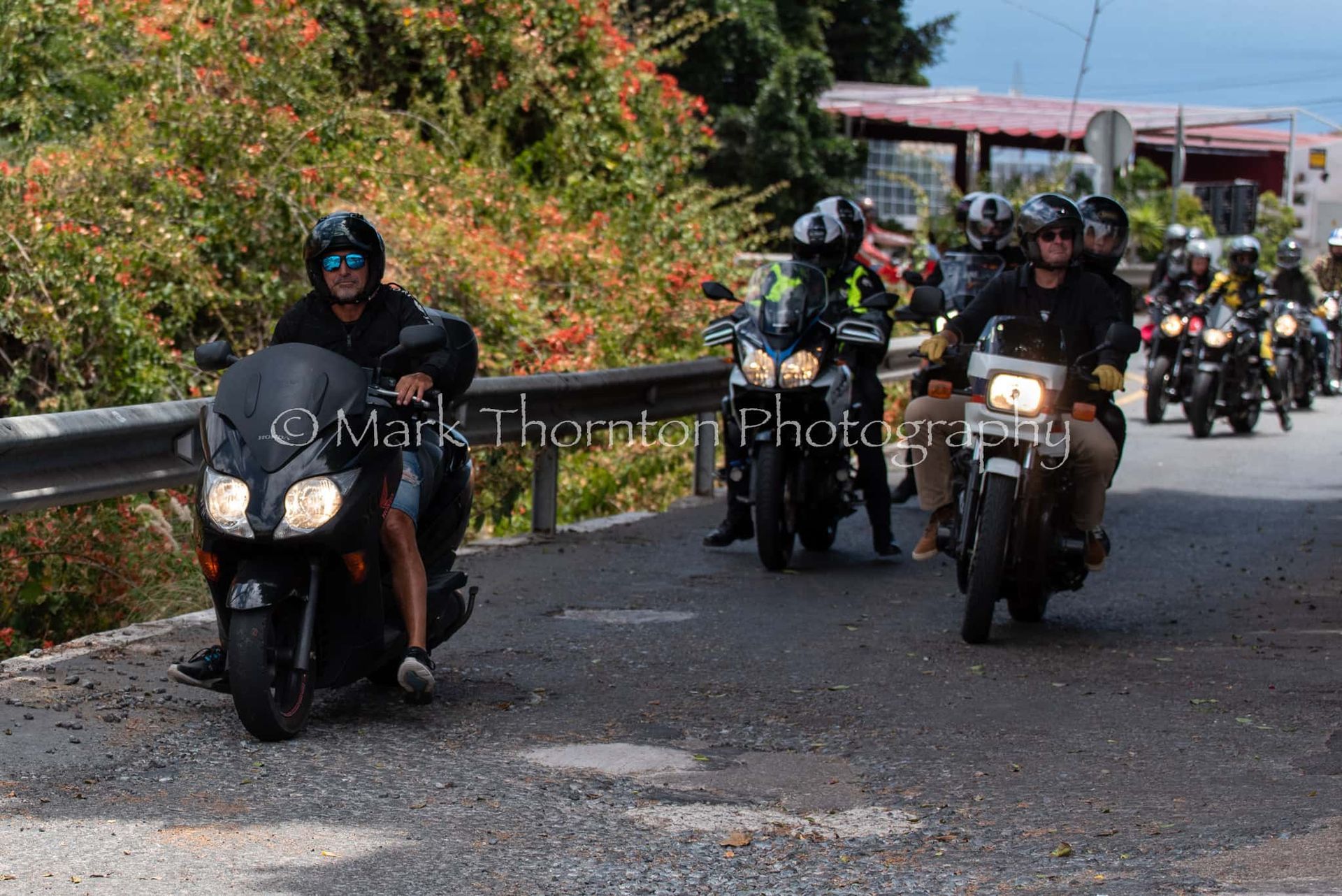 A group of people are riding motorcycles down a road.