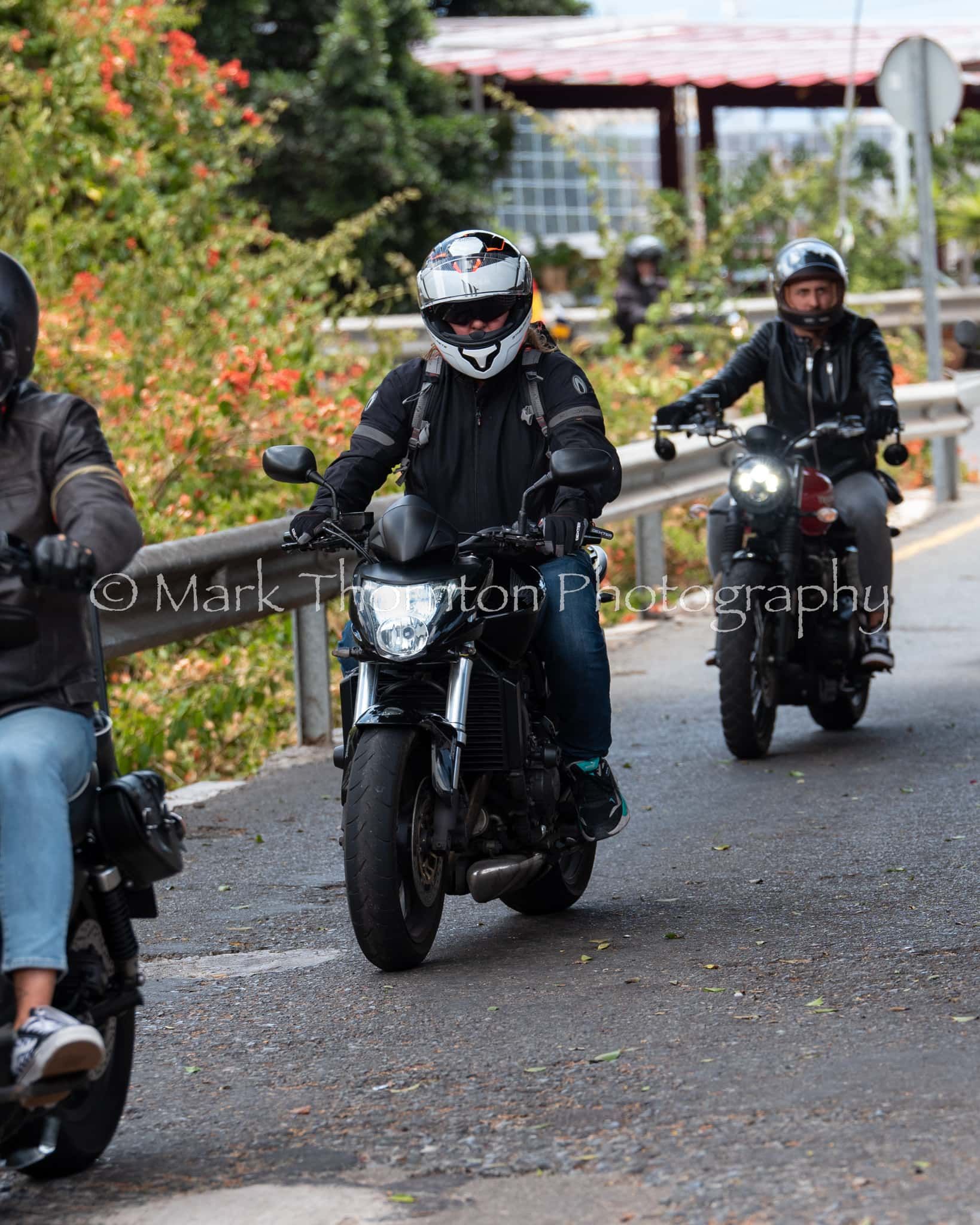A group of people are riding motorcycles down a road.