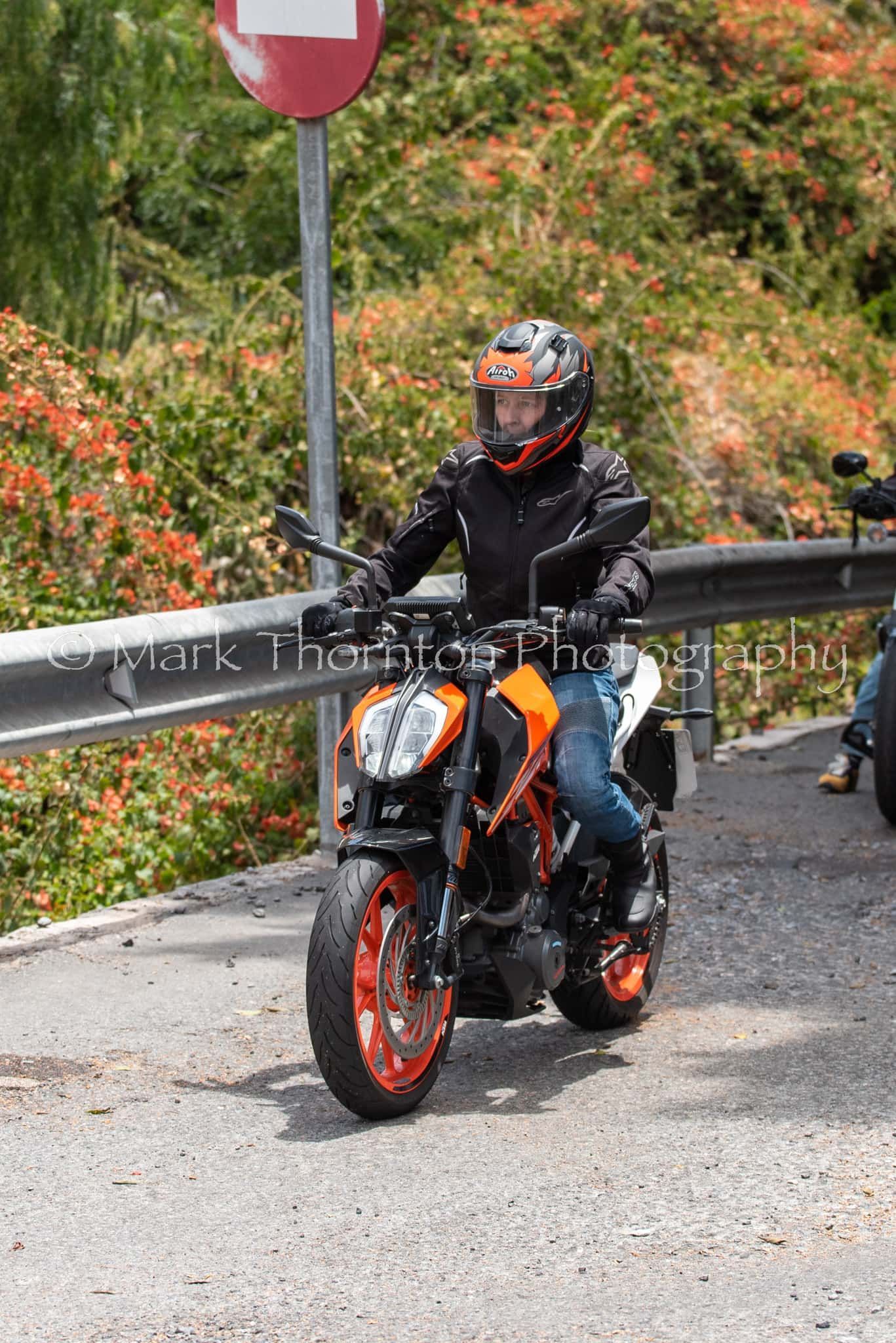 A man is riding a motorcycle down a road.