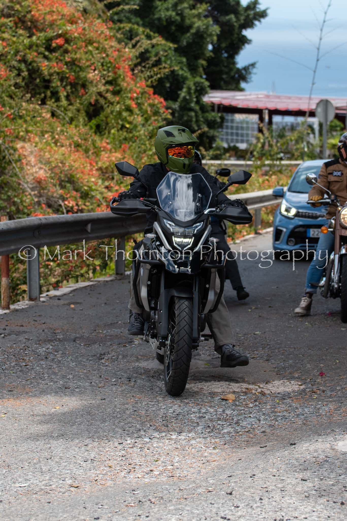A man is riding a motorcycle down a dirt road.