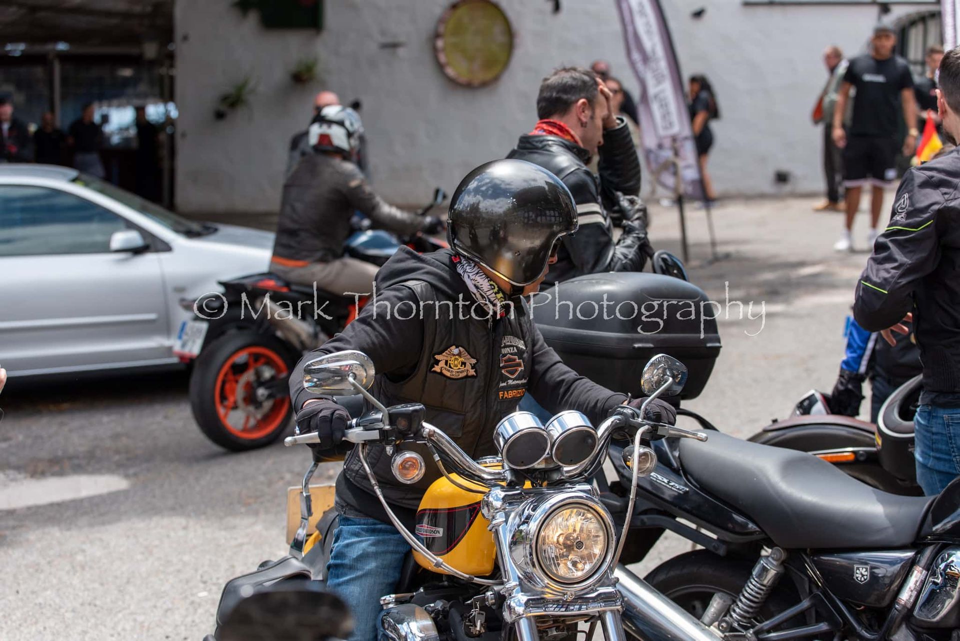 A man is sitting on a yellow and black motorcycle