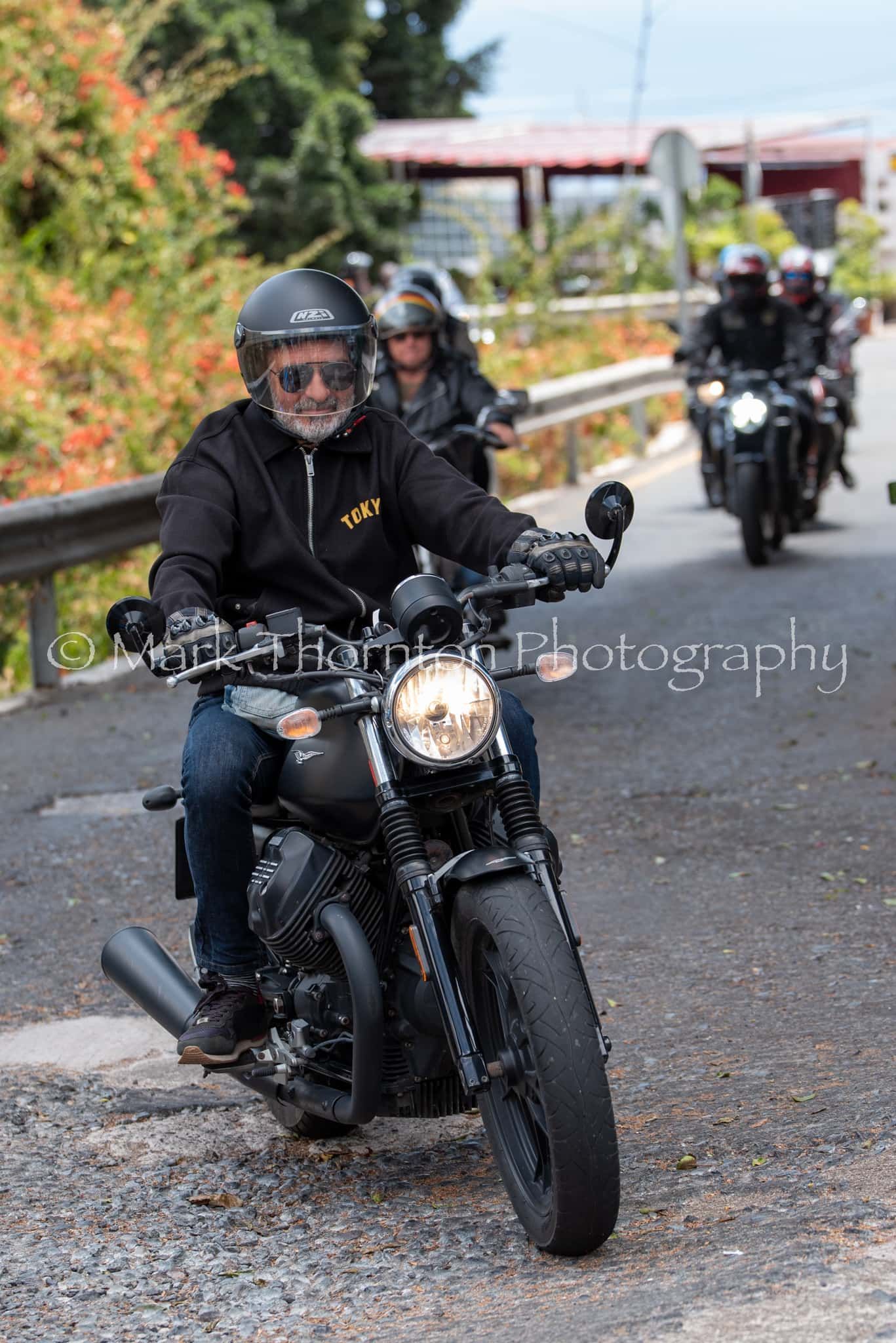 A group of people are riding motorcycles down a road.
