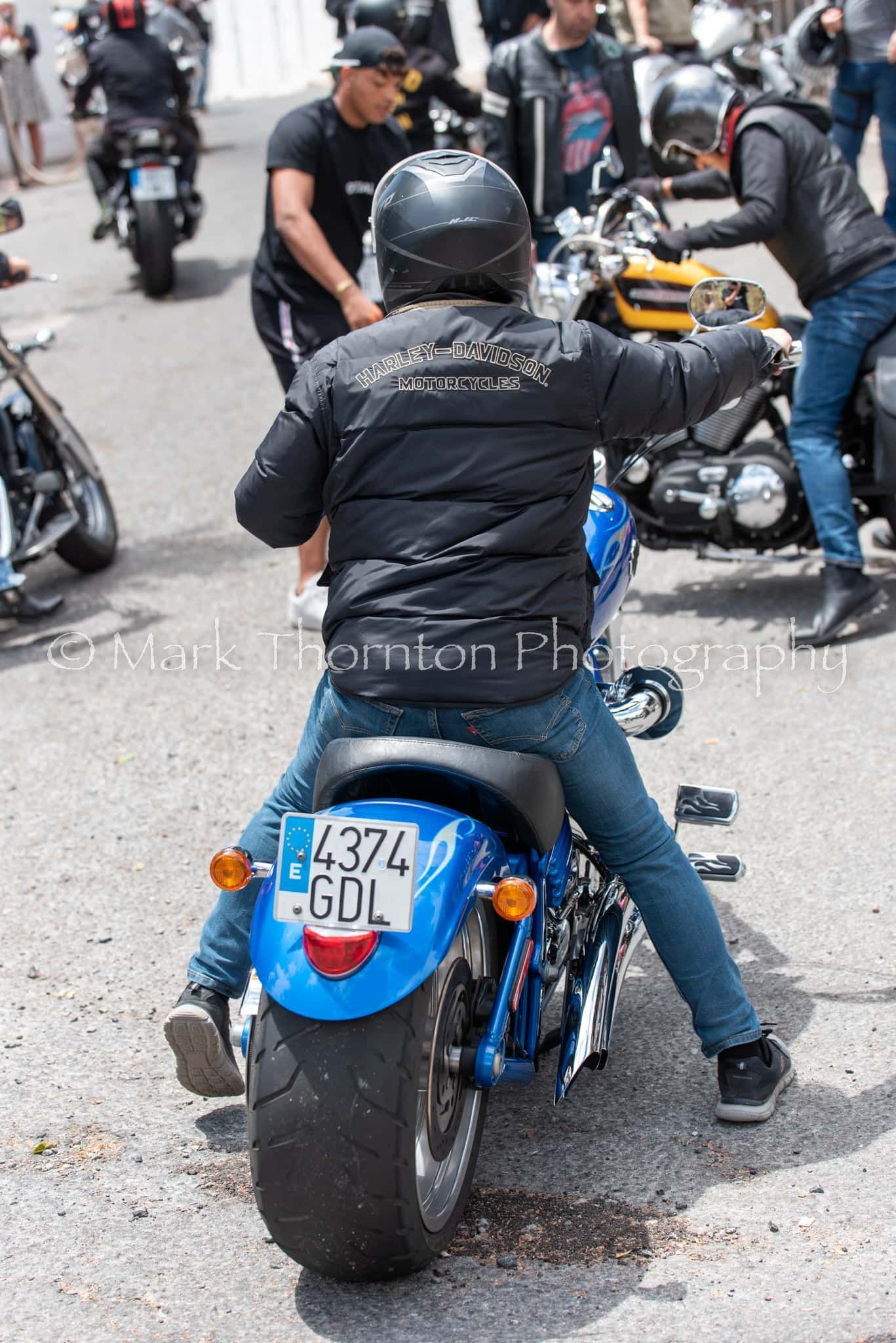 A man is riding a blue motorcycle with a license plate that says gol