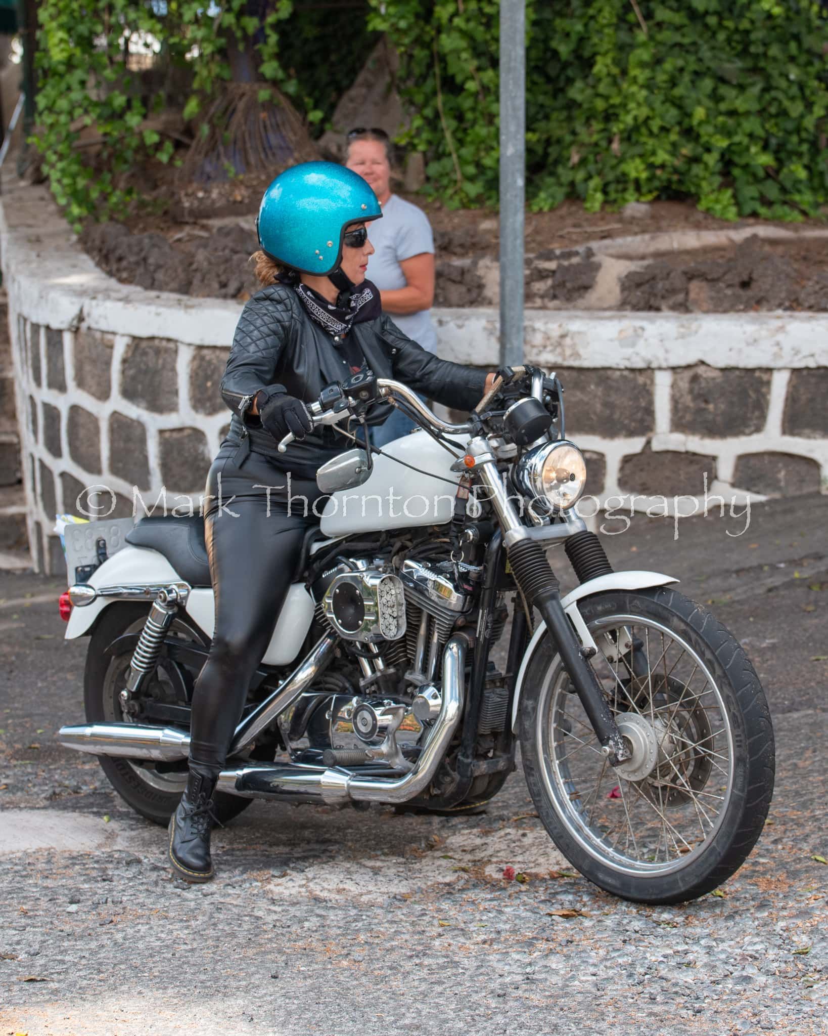 A woman wearing a blue helmet is riding a motorcycle