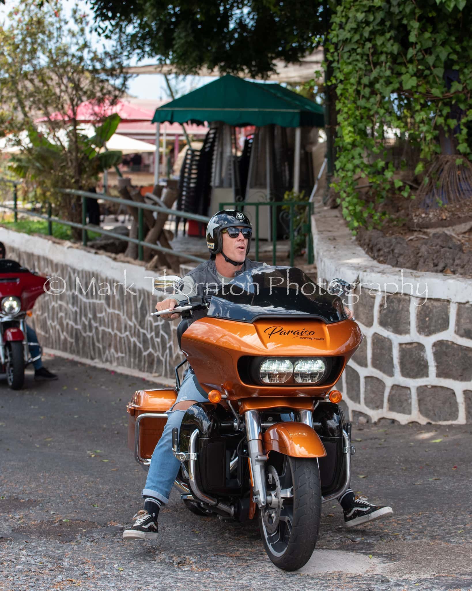 A man is riding an orange harley davidson motorcycle
