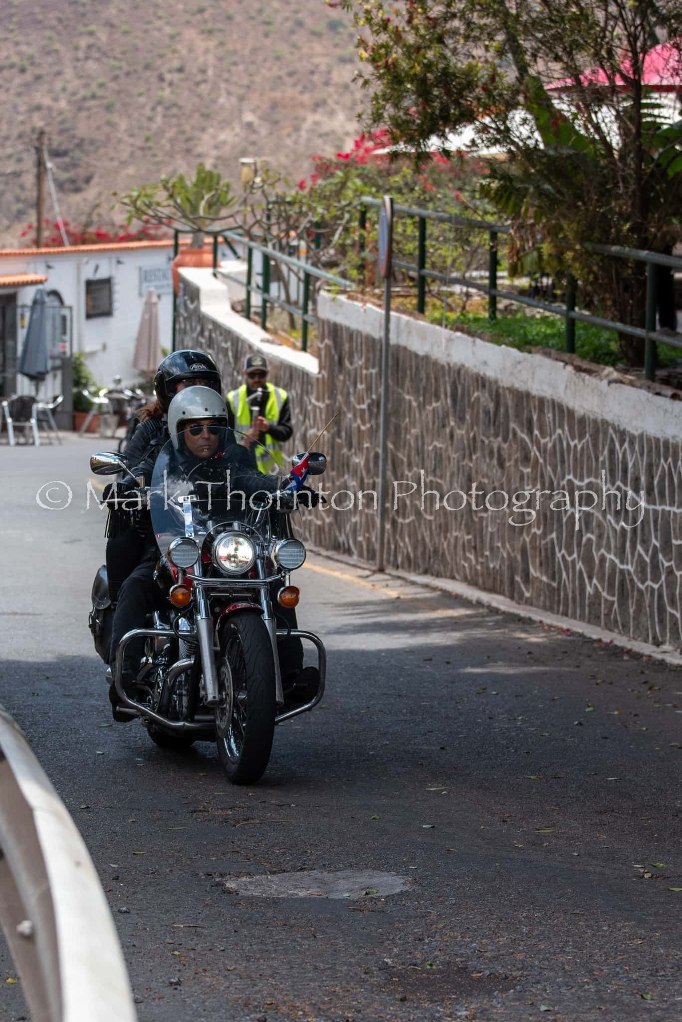 A man is riding a motorcycle down a street