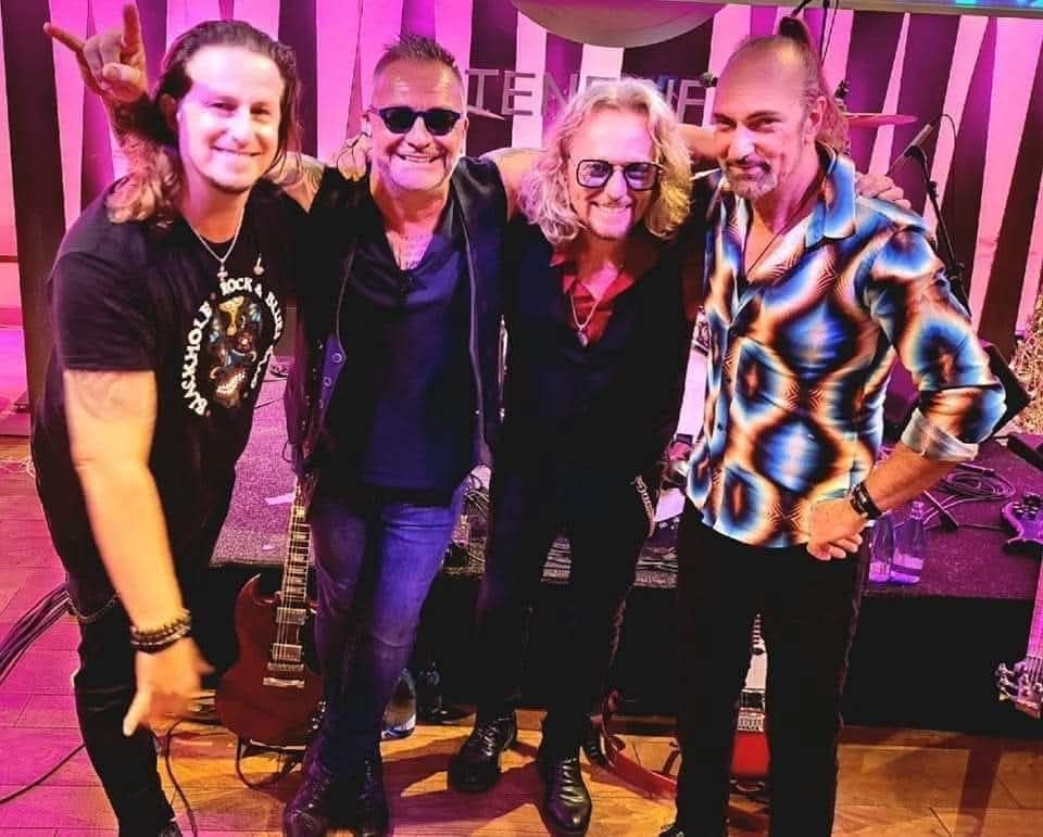A group of men are posing for a picture in front of a stage.