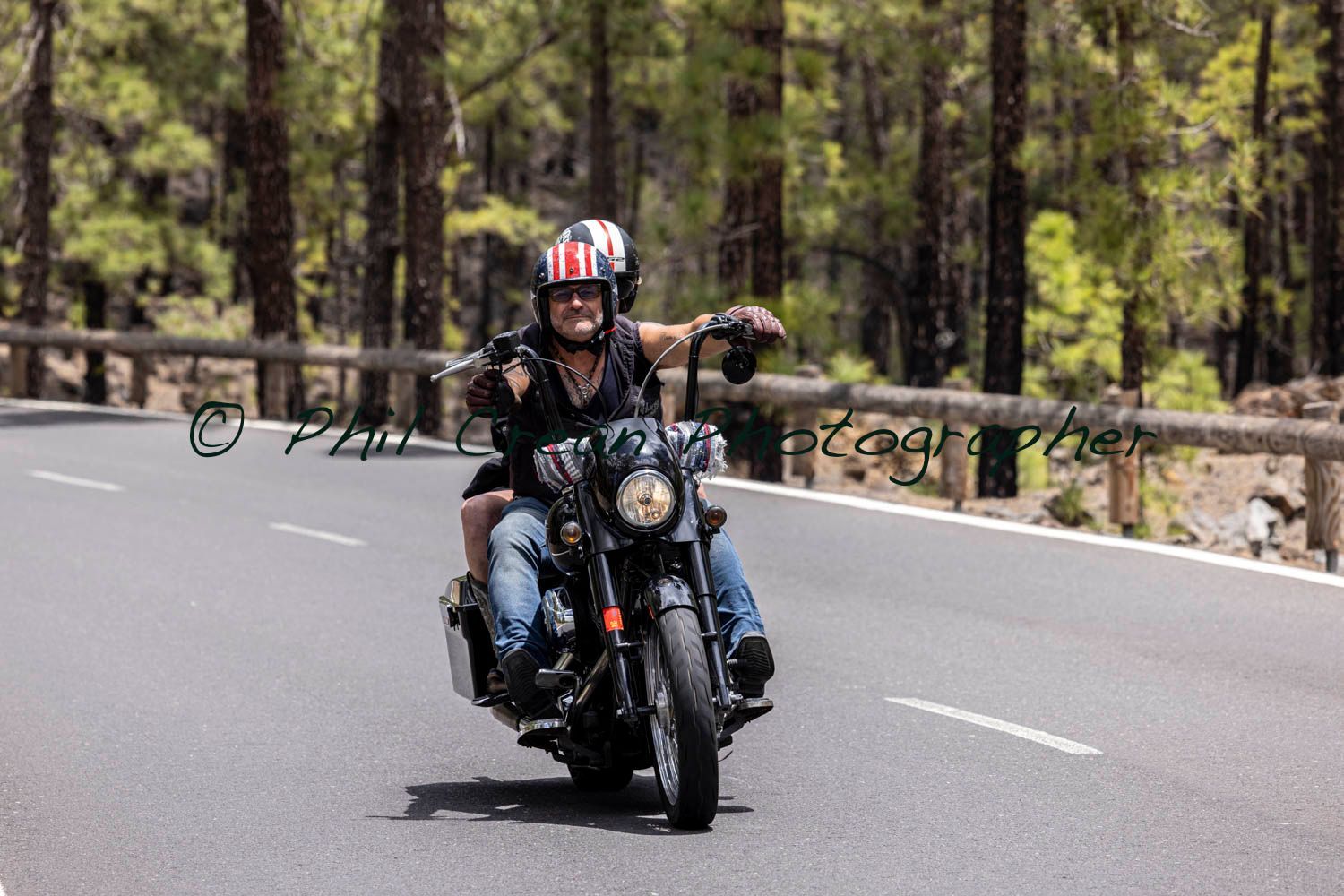 A man and a woman are riding a motorcycle down a road.