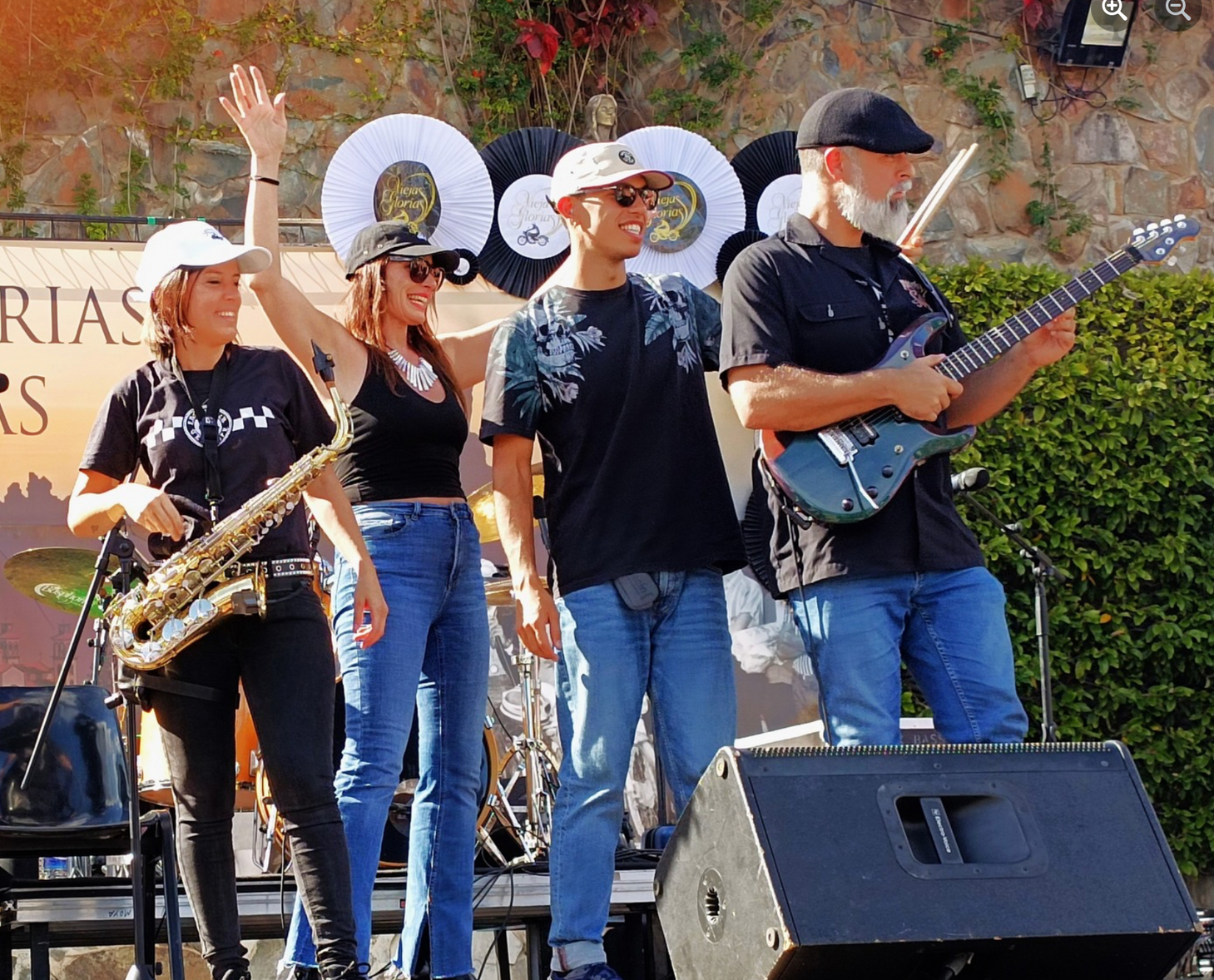 A group of people playing instruments on a stage with a sign in the background that says rias