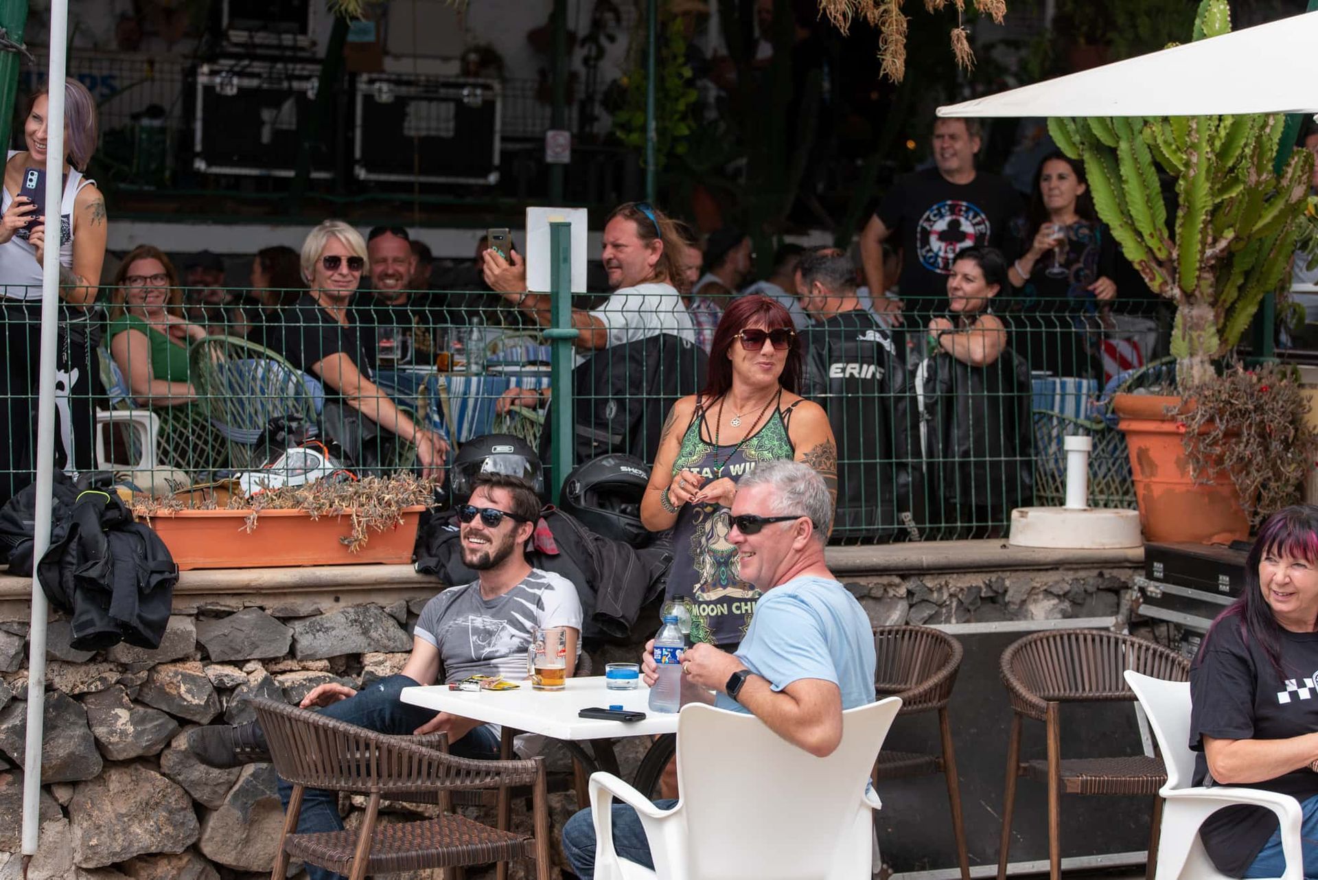 A group of people are sitting at tables outside of a restaurant.