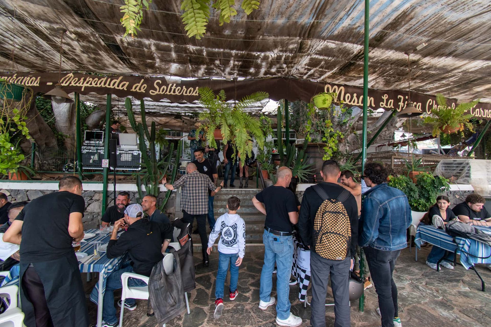 A group of people are sitting at tables under a canopy in a restaurant.
