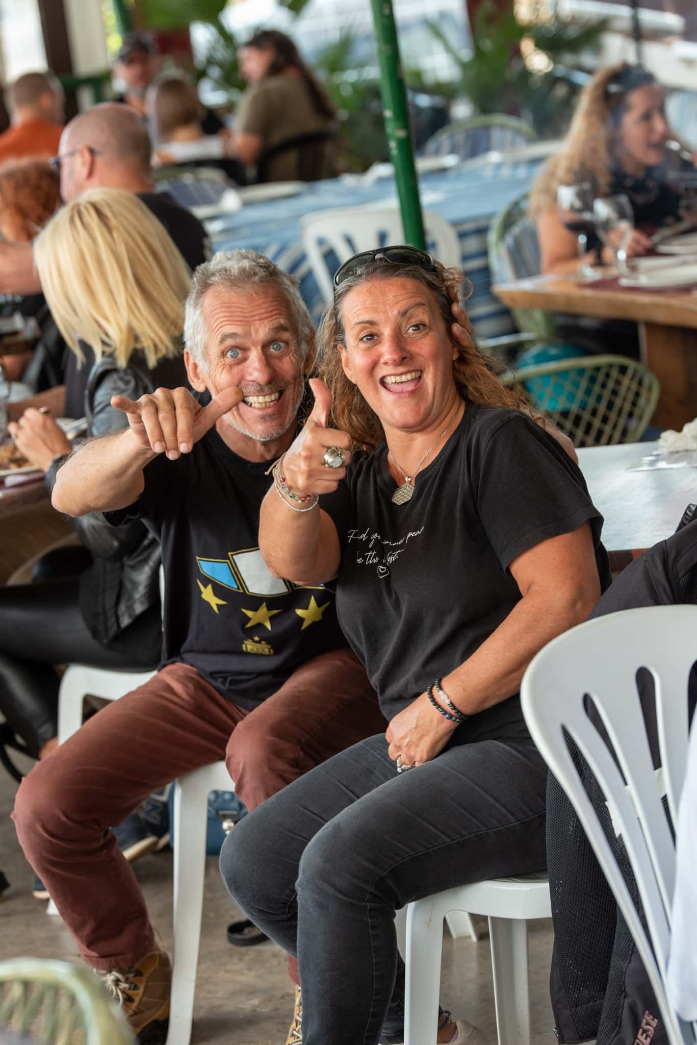 A man and a woman are sitting next to each other in a restaurant giving a thumbs up.