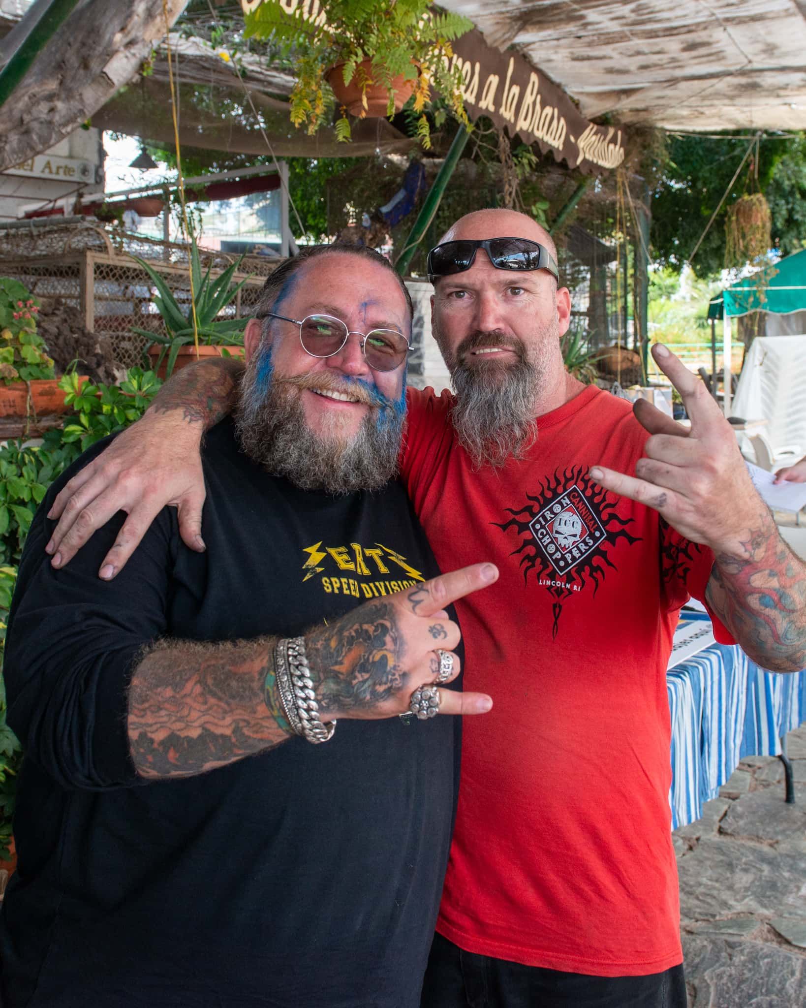 Two men are posing for a picture and one has a tattoo on his face