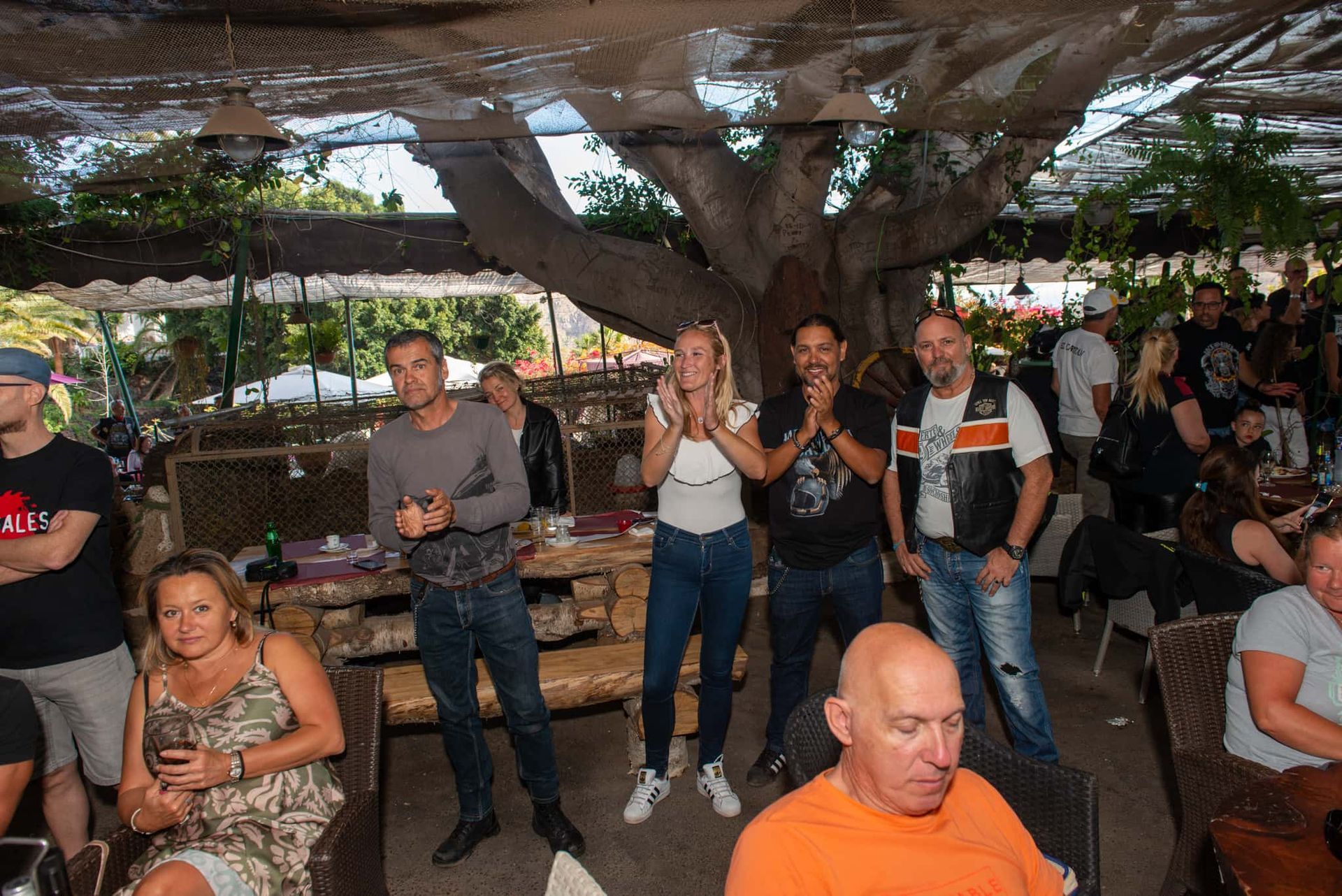 A group of people are standing in a restaurant under a canopy.