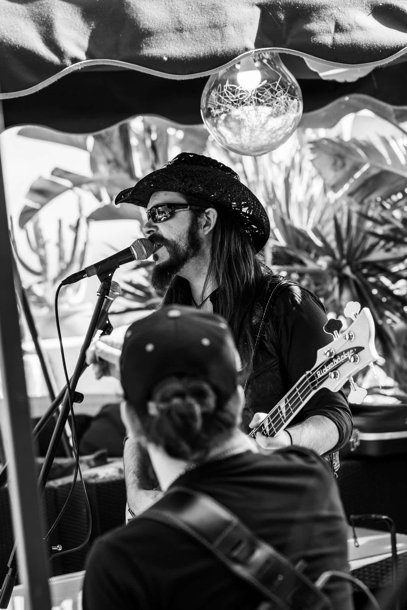 A man with dreadlocks is singing into a microphone while playing a guitar.