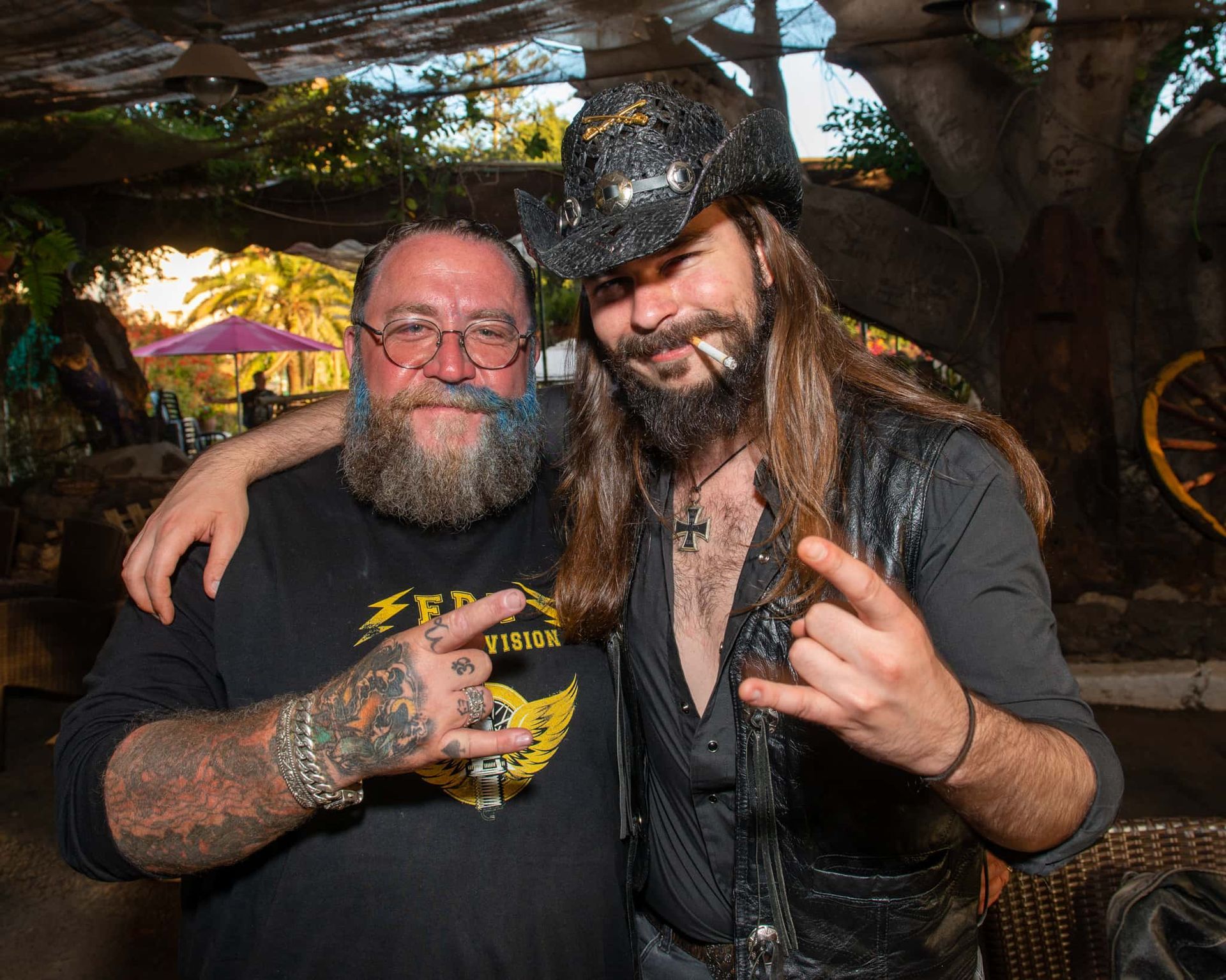 Two men are posing for a picture and one is wearing a cowboy hat