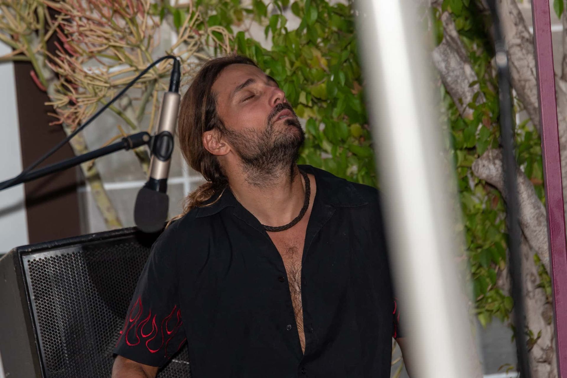 A man with a beard is standing in front of a microphone.