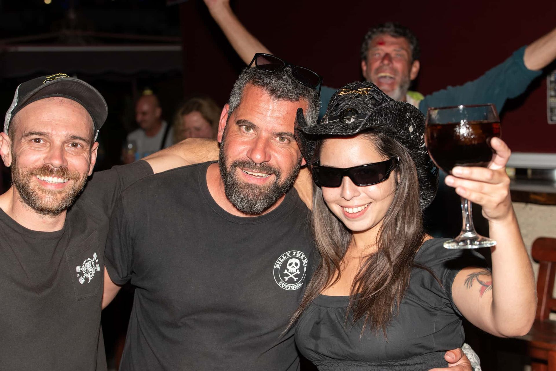 A group of people posing for a picture with one woman holding a glass of wine