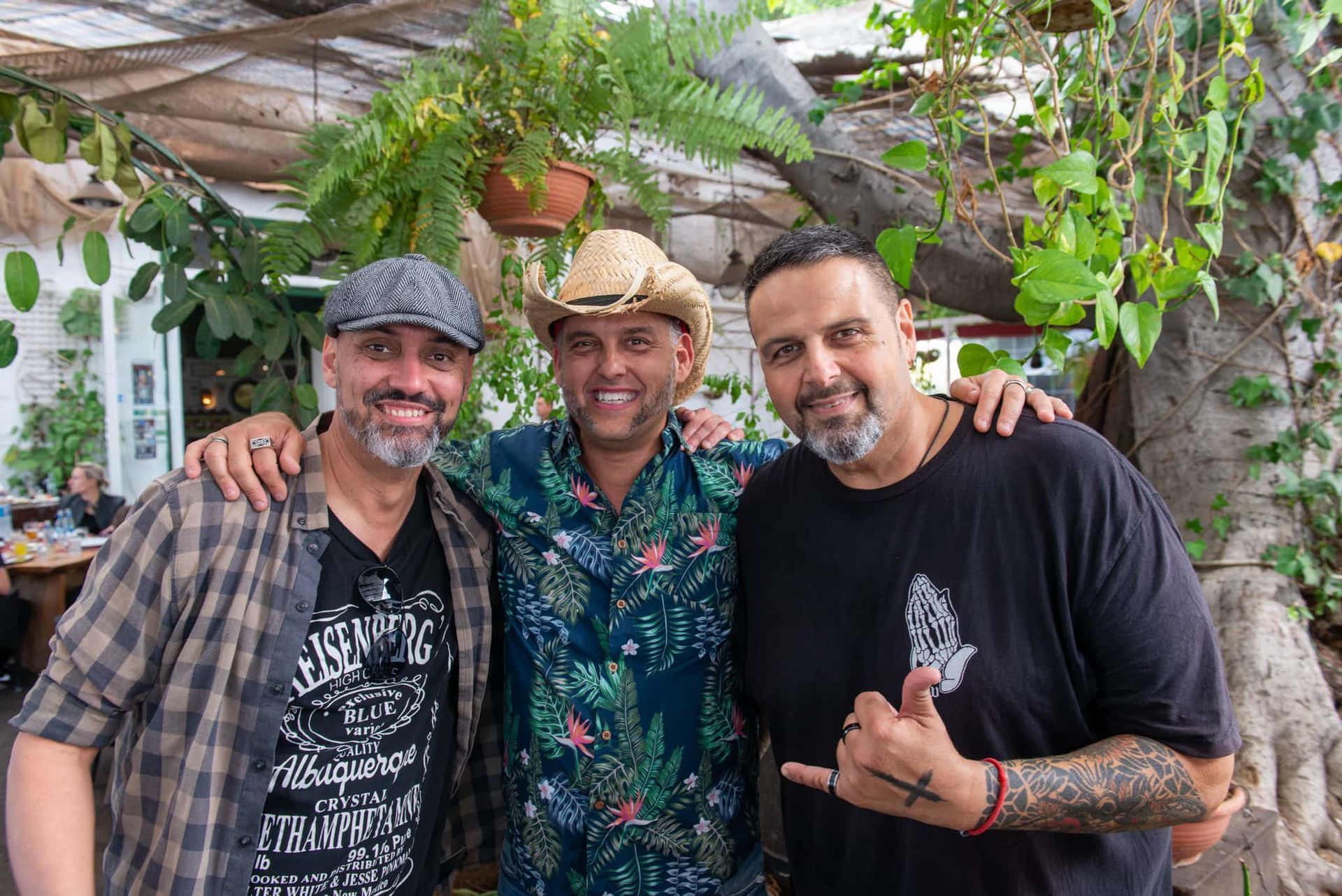 Three men are posing for a picture together in front of a tree.