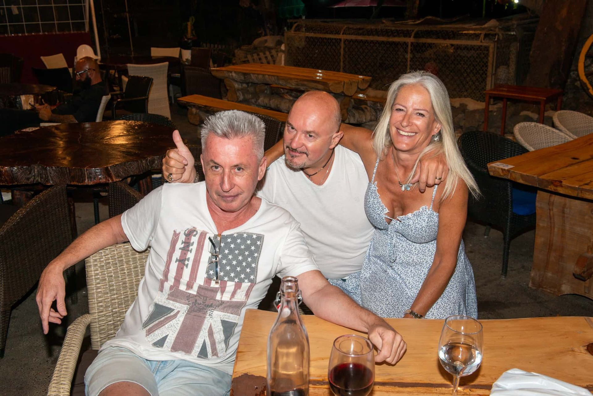 Three people are posing for a picture at a table in a restaurant.