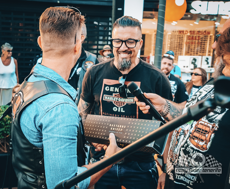 A man wearing a harley davidson shirt is talking into a microphone