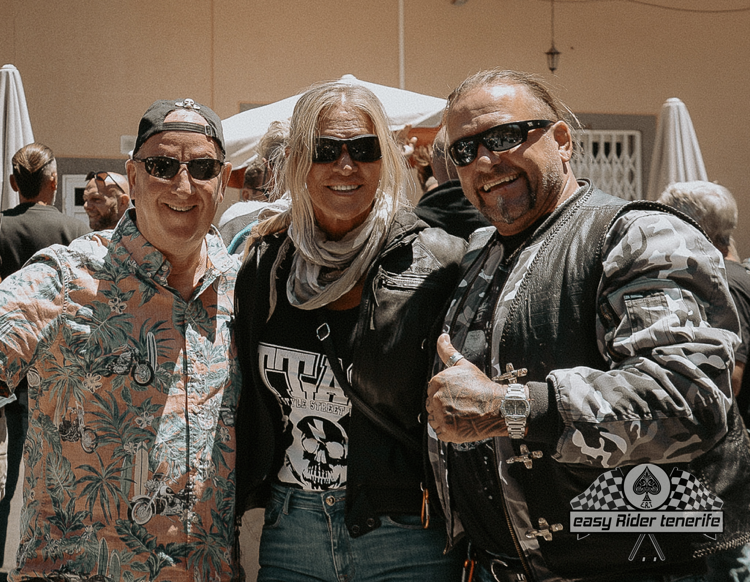 Three men are posing for a picture and one of them is wearing sunglasses.
