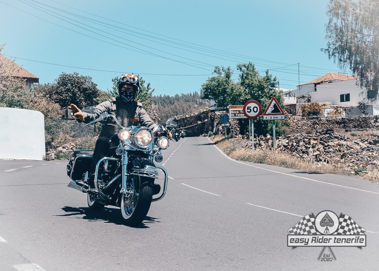 A man is riding a motorcycle down a road with a speed limit of 60