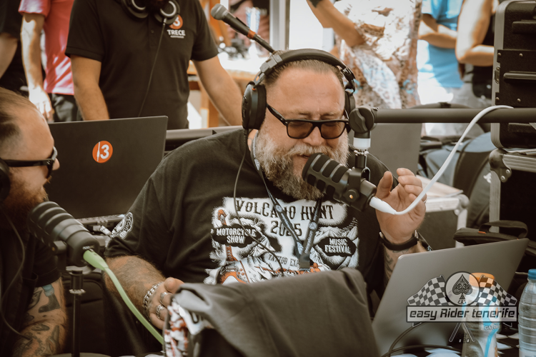 A man with a beard is wearing headphones and talking into a microphone.